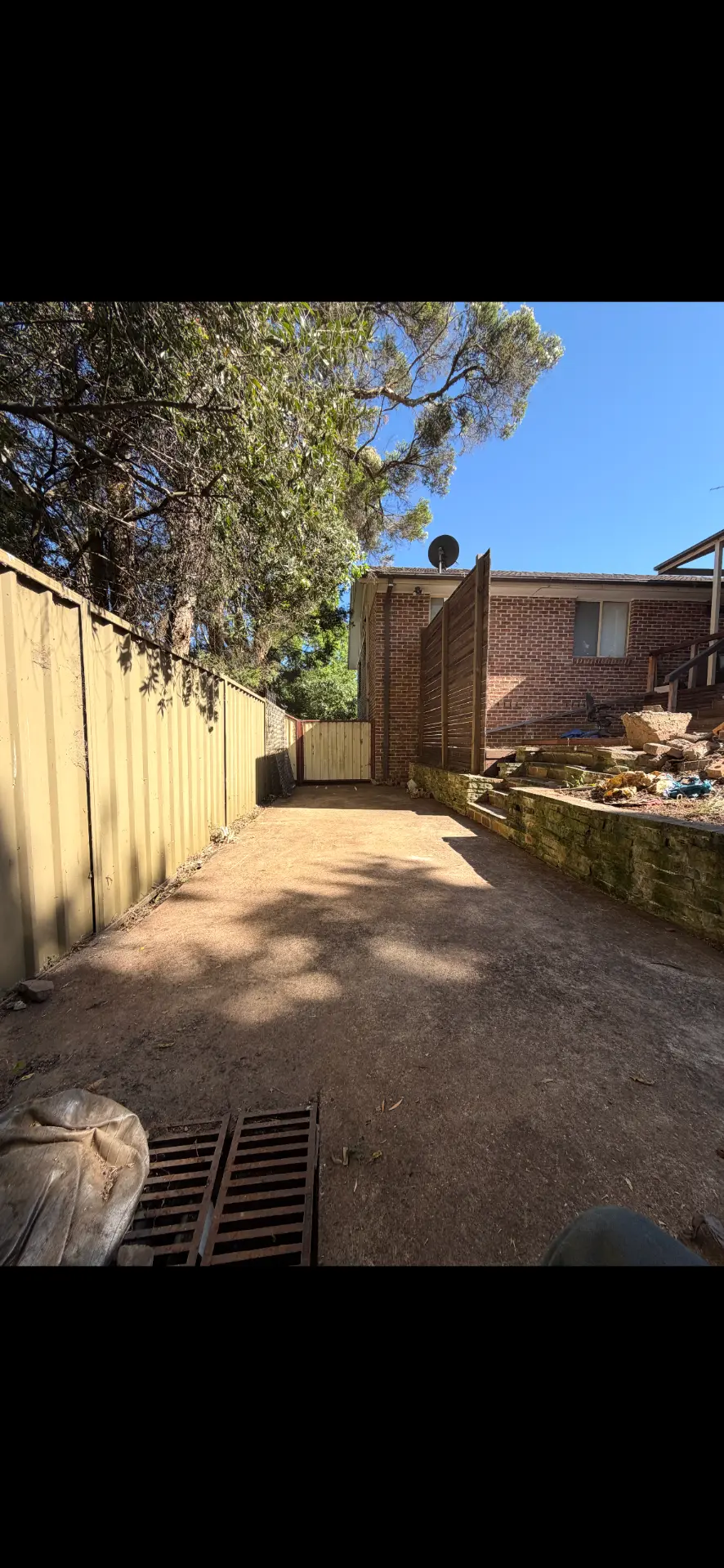 Side yard cleared and graded back to bare earth beside a new timber gate